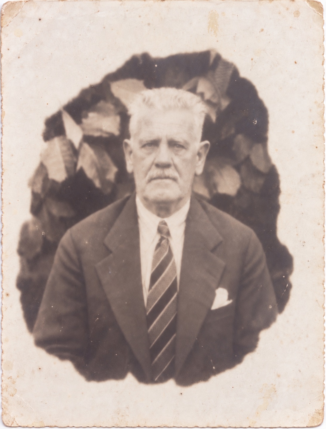 Interpretation of an aged family portrait: an older man in a suit, with facial features altered and worn paper and white vignette preserved.